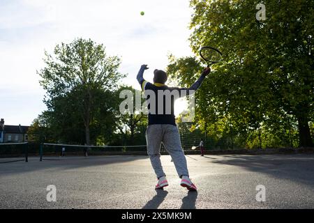 Uomo che gioca a tennis sul campo di quartiere Foto Stock