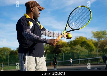 Uomo che gioca a tennis sul campo di quartiere Foto Stock