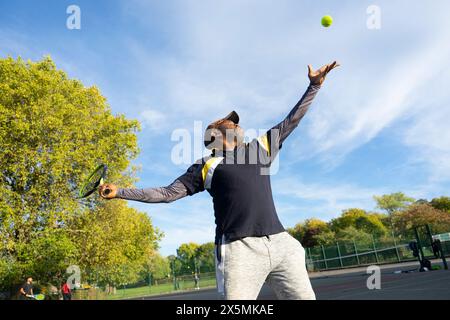 Uomo che gioca a tennis sul campo di quartiere Foto Stock