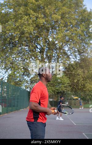 Uomo che gioca a tennis sul campo di quartiere Foto Stock