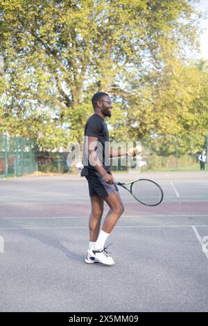 Uomo che gioca a tennis sul campo di quartiere Foto Stock