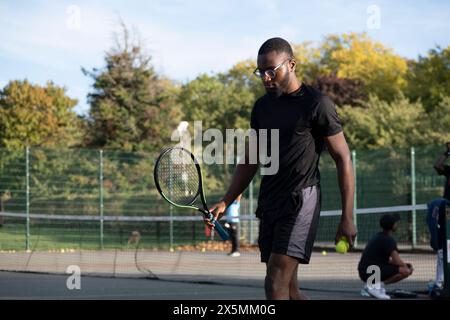 Uomo che gioca a tennis sul campo di quartiere Foto Stock