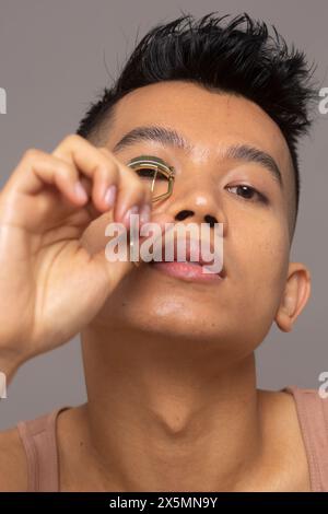 Primo piano di una persona che arriccia le ciglia con l'arricciacapelli Foto Stock