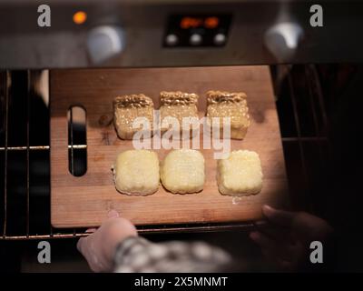 Donna che mette le torte lunari in forno Foto Stock