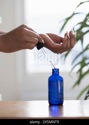 Primo piano delle mani delle donne che tengono la pipetta con siero facciale Foto Stock