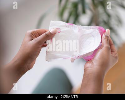 Primo piano di donne che si dispiegano a mano un cuscinetto sanitario Foto Stock