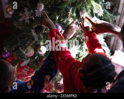 Padre con figli che appendono ornamenti sull'albero di Natale Foto Stock