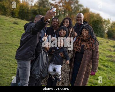 Ritratto di una famiglia multi-generazionale che scatta selfie nel prato Foto Stock