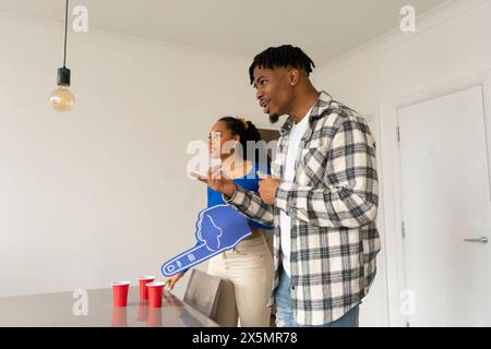 Amici che parlano mentre giocano a beer pong a una festa a casa Foto Stock