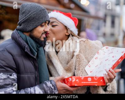 Una giovane coppia che tiene una scatola al mercatino di Natale Foto Stock