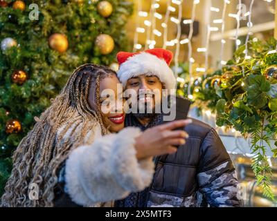 Coppia sorridente che fa selfie con il cappello di Babbo Natale Foto Stock