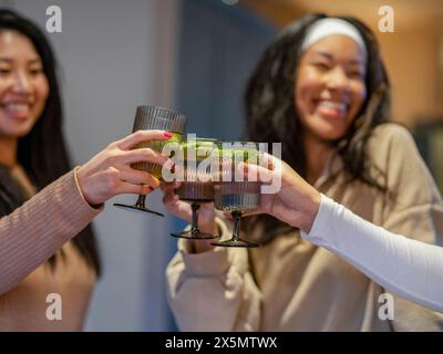 Amiche che fanno un brindisi celebrativo a casa Foto Stock