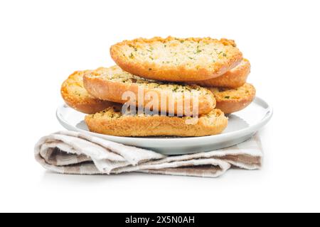 Fette di pane croccanti all'aglio ricoperte di erbe sul piatto isolate su sfondo bianco. Foto Stock