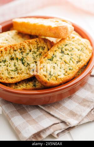 Fette di pane croccanti all'aglio ricoperte di erbe aromatiche in un recipiente. Foto Stock