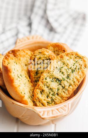 Fette di pane croccanti all'aglio ricoperte di erbe aromatiche in un recipiente. Foto Stock