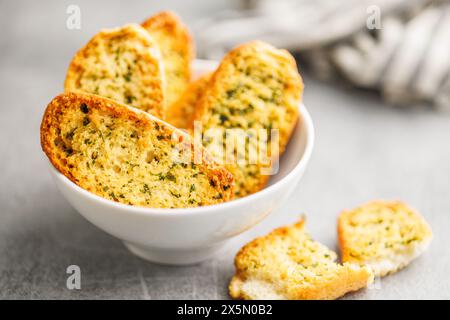 Fette di pane croccanti all'aglio ricoperte di erbe aromatiche in un recipiente. Foto Stock