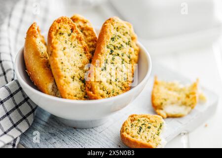 Fette di pane croccanti all'aglio ricoperte di erbe aromatiche in un recipiente. Foto Stock