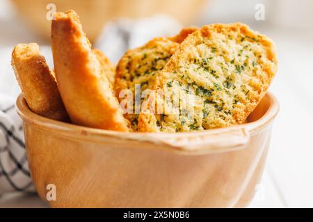 Fette di pane croccanti all'aglio ricoperte di erbe aromatiche in un recipiente. Foto Stock