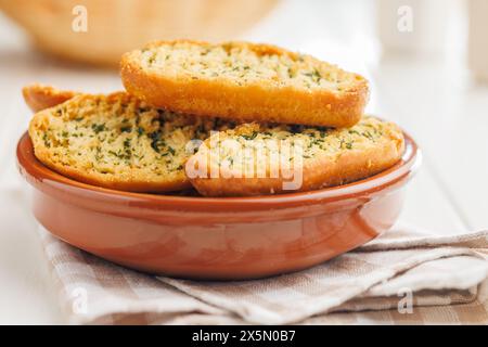 Fette di pane croccanti all'aglio ricoperte di erbe aromatiche in un recipiente. Foto Stock