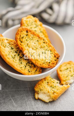 Fette di pane croccanti all'aglio ricoperte di erbe aromatiche in un recipiente. Foto Stock