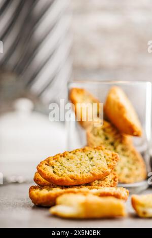 Fette di pane croccanti all'aglio ricoperte di erbe su un tavolo da cucina. Foto Stock