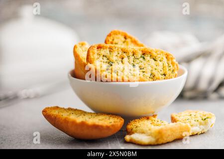 Fette di pane croccanti all'aglio ricoperte di erbe aromatiche in un recipiente. Foto Stock