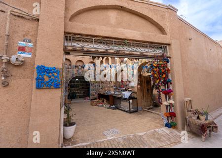 Yazd, Iran - 2024-03-03: Un negozio di decorazione locale espone vibranti artigianato persiano in uno storico edificio in mattoni. Foto Stock