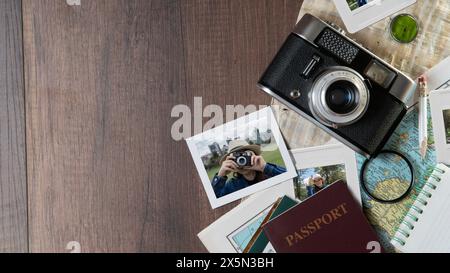 Vista dall'alto delle fotografie di una donna che scatta foto, passaporti, vecchia fotocamera, mappa e quaderno su un tavolo di legno scuro Foto Stock