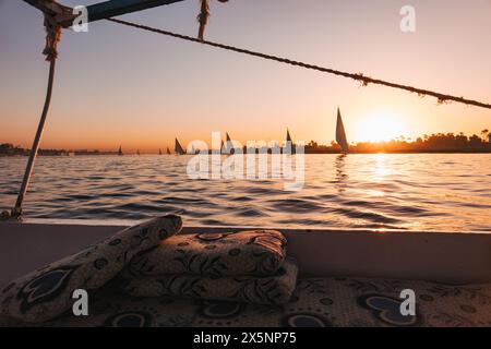 Le barche a vela si crogiolano alla luce dorata del tramonto sul Nilo vicino a Luxor, in Egitto Foto Stock