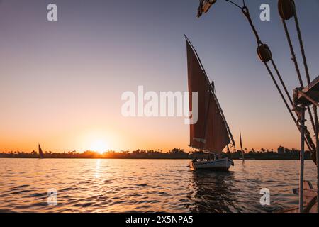 Le barche a vela si crogiolano alla luce dorata del tramonto sul Nilo vicino a Luxor, in Egitto Foto Stock