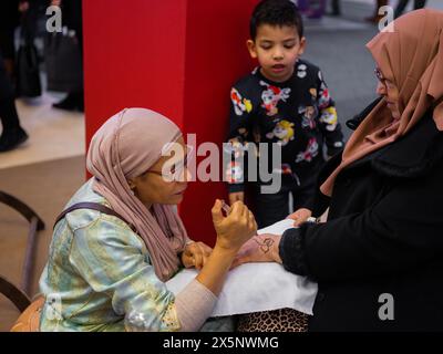 Berlino, Germania 20.01. 2023 Mehndi maestro che disegna tatuaggio all'henné su mano femminile, arte mehendi Foto Stock