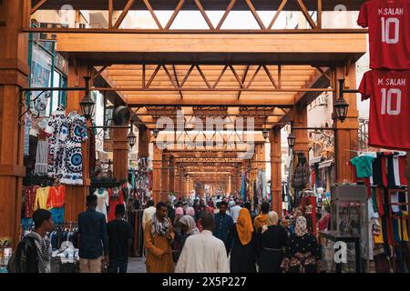 Le persone curiosano in un pedonale con vari souvenir che conducono alla stazione ferroviaria principale della città di Assuan, nell'Egitto meridionale Foto Stock