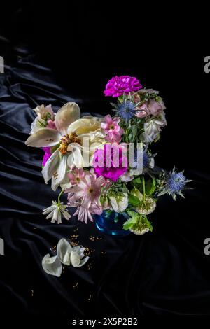 Cattura l'essenza della transitorietà: I fiori induriti si stagliano con grazia in un sereno vaso blu, evocando un senso di nostalgia poetica sullo sfondo Foto Stock