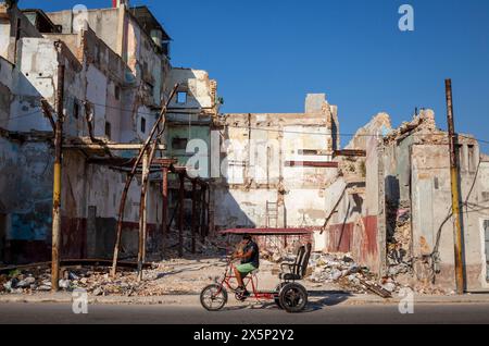 Il pedalò passa per un edificio crollato nel centro di Havana, Cuba Foto Stock