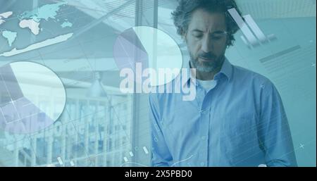 Uomo di mezza età caucasico in camicia blu che analizza grafici digitali Foto Stock