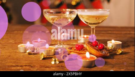 I bicchieri da champagne si appoggiano su un tavolo con candele accese e decorazioni natalizie Foto Stock
