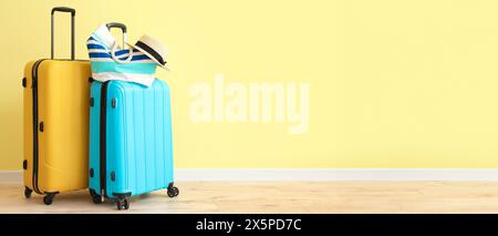 Valigie e accessori da spiaggia confezionati su sfondo giallo con spazio per il testo. Concetto di viaggio Foto Stock