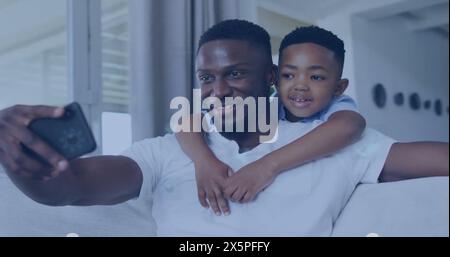 Padre e figlio afroamericani con i capelli neri corti fanno un selfie su un divano Foto Stock