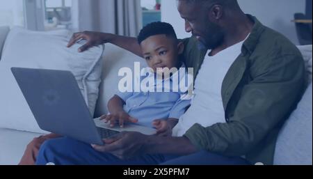 Padre e figlio afroamericani seduti sul divano, guardando un computer portatile Foto Stock