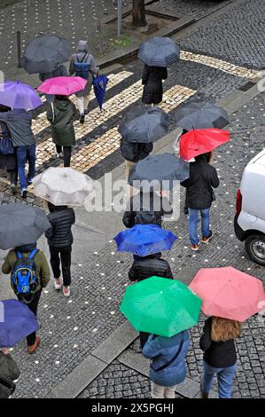 Persone che attraversano una strada con ombrelli colorati in una giornata di pioggia a Porto, Portogallo, Europa Foto Stock