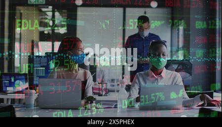 Immagine di un tabellone commerciale e grafico su diversi colleghi che indossano una maschera che parla e lavora su un computer portatile Foto Stock