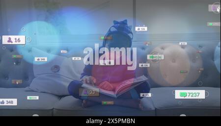 Immagine di icone dei social media e punti di luce su un ragazzo birazziale che legge un libro a casa Foto Stock