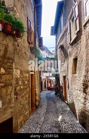 Pittoresca strada acciottolata con edifici storici in pietra e fioriere in un affascinante villaggio italiano Foto Stock