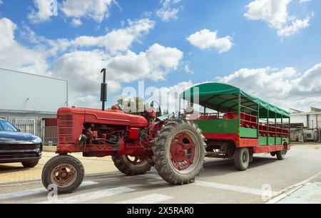 Vecchio trattore con carrello per il trasporto di persone attraverso la campagna Foto Stock