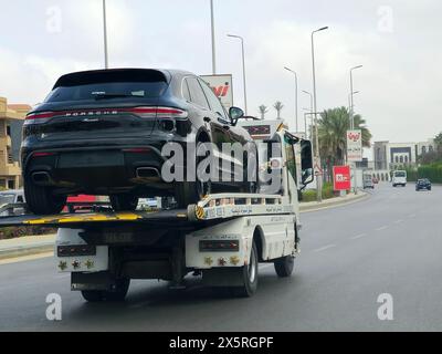 Cairo, Egitto, aprile 27 2024: Un carro attrezzi idraulico con pianale con una nuova Porsche Macan, un SUV crossover compatto di lusso (D-segmen) Foto Stock