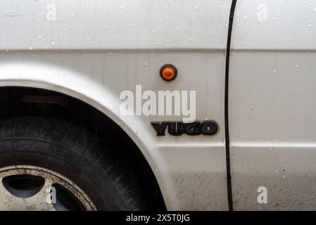 Dettaglio laterale che mostra l'indicatore rotondo e il logo di una classica auto Yugo, prodotta in Jugoslavia. maggio 2024 Foto Stock