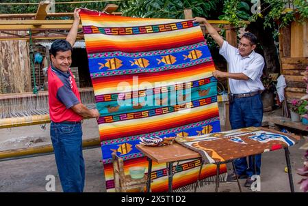 Santa Ana del Valle, Oaxaca, Messico. Il tessitore Ernesto Martinez Cruz (a sinistra) mostra uno dei suoi tappeti. Foto Stock