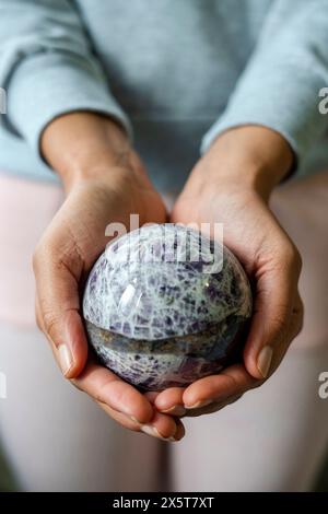 Primo piano di mani femminili che tengono la sfera di cristallo Foto Stock