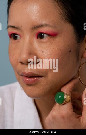 Donna adulta che indossa un'ombretto rosa e un anello verde Foto Stock