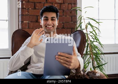 Un giovane sorridente che fa videochiamata sul tablet Foto Stock